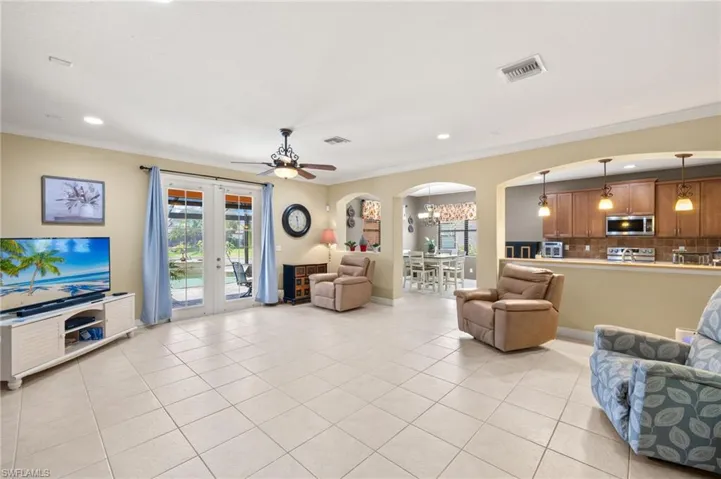 Great room featuring crown molding, arched walkways, visible vents, and light tile patterned floors