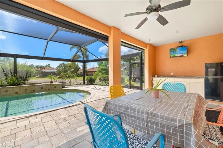 Outdoor pool area with hurricane screens, ceiling fan, outdoor kitchen