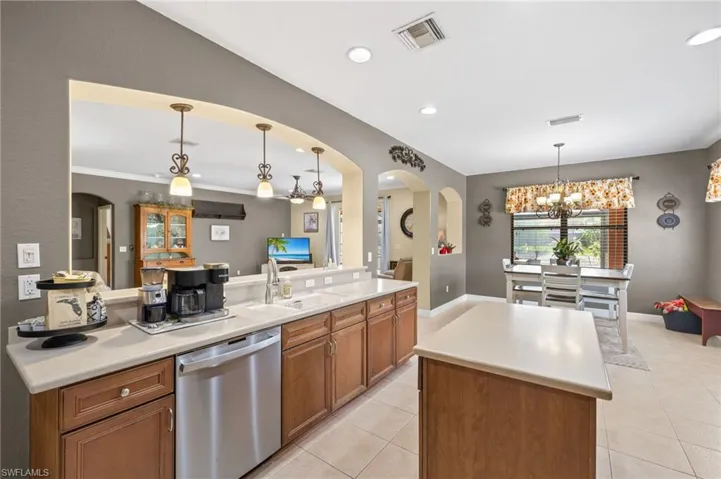 Kitchen featuring stainless steel dishwasher, a sink, light tile patterned flooring, and visible vents