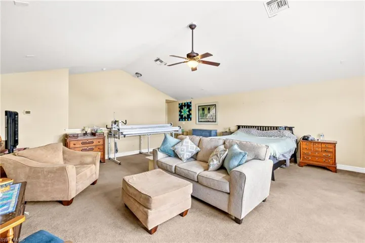 Loft area featuring light carpet, vaulted ceiling, and visible vents
