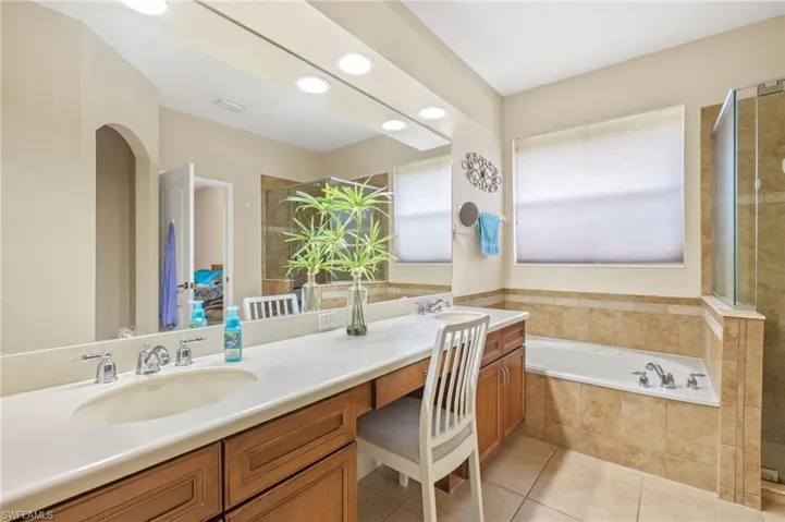 Full bath featuring double vanity, a sink, a garden tub, and tile patterned flooring