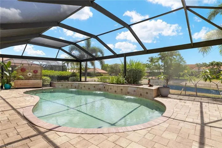 Outdoor pool featuring a lanai and a patio area overlooking a community pond