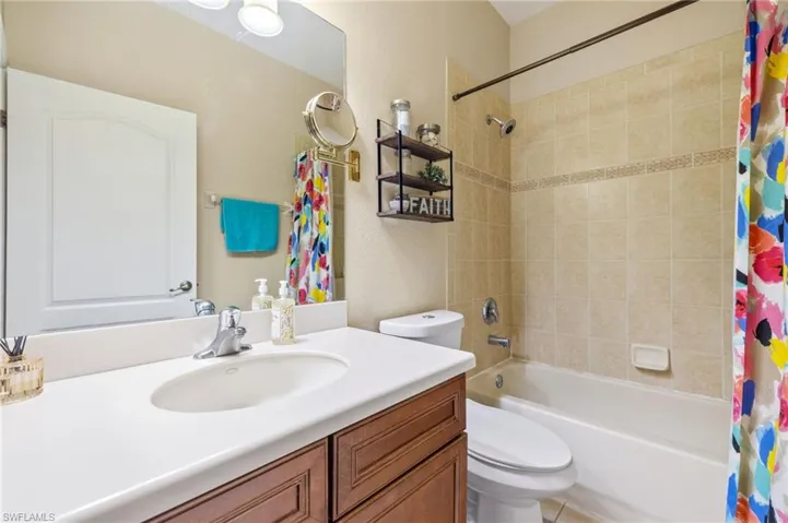 Bathroom featuring vanity, shower / bathtub combination with curtain, and toilet