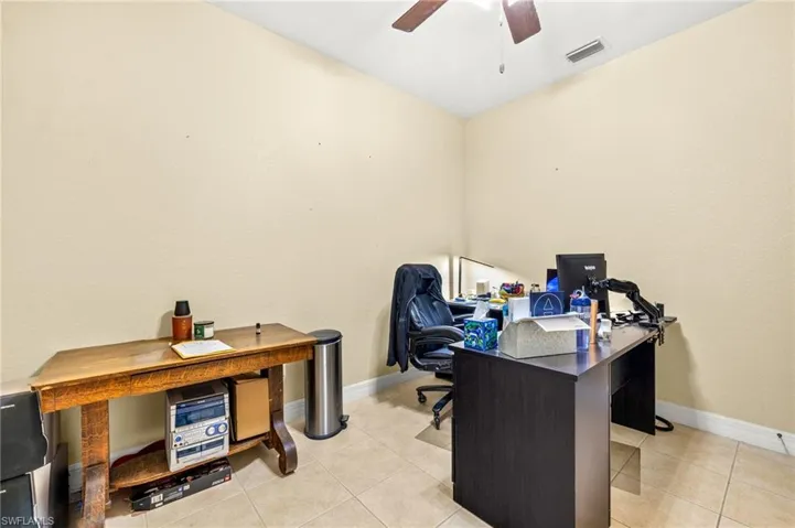 Bedroom used as an Office space with visible vents, baseboards, ceiling fan, and light tile patterned floors