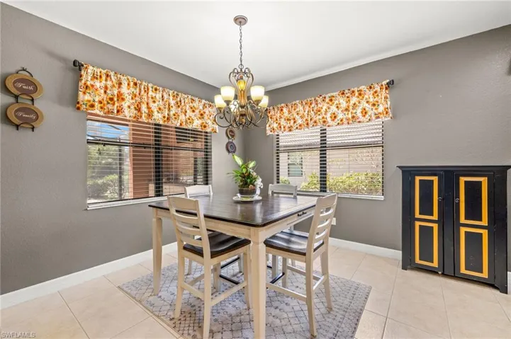 Breakfast area featuring baseboards, light tile patterned flooring, a chandelier, and a wealth of natural light