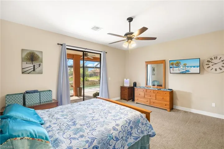 Carpeted bedroom featuring a ceiling fan, baseboards, visible vents, and access to exterior