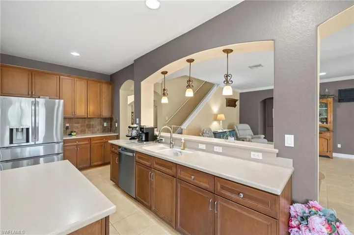 Kitchen with arched walkways, a sink, light tile patterned floors, and stainless steel appliances