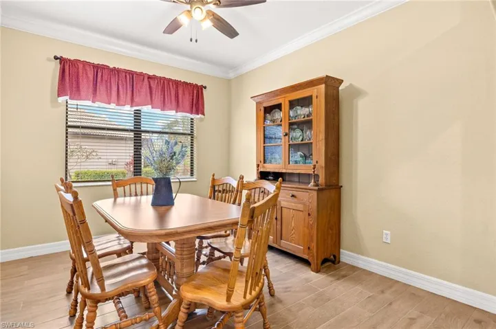 Dining space featuring a ceiling fan, baseboards, ornamental molding, and light wood-style flooring