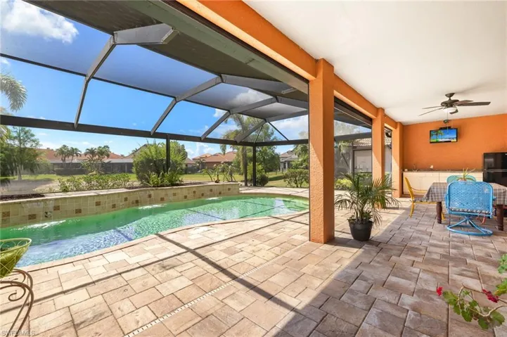 Outdoor pool with screen enclosure, ceiling fan, and a patio area