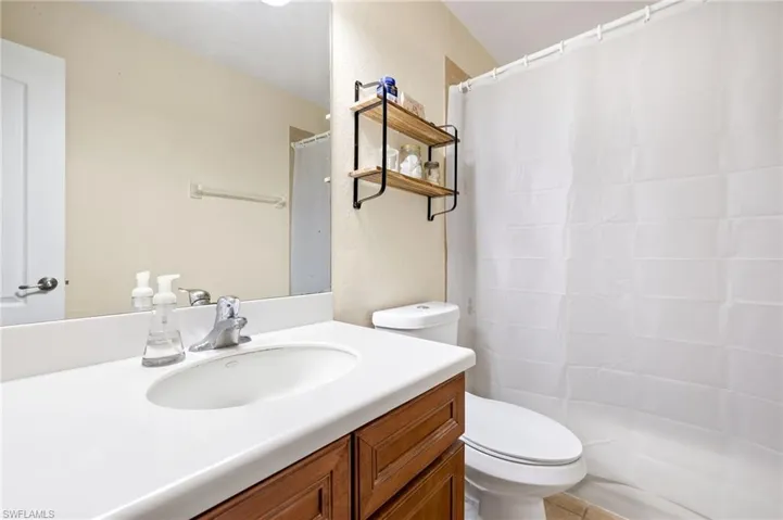 Bathroom featuring vanity, a textured wall, curtained shower, and toilet