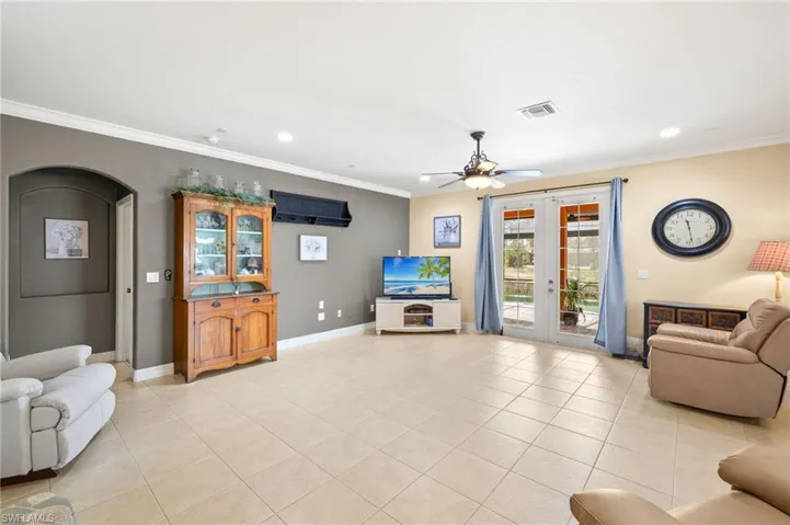 Living area featuring french doors, ornamental molding, ceiling fan, and light tile patterned floors