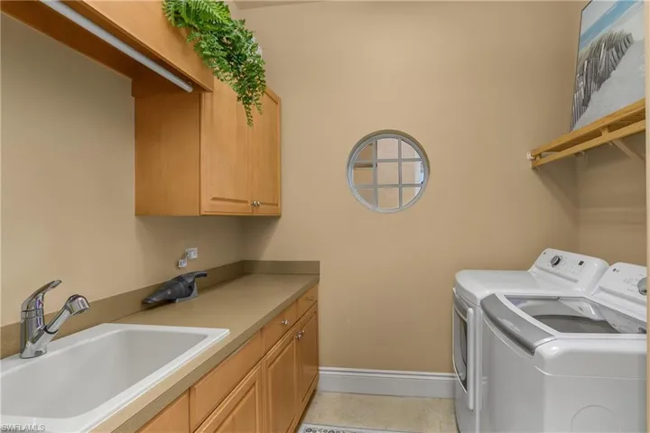 Laundry area featuring washing machine and dryer, light tile patterned flooring, and cabinet space