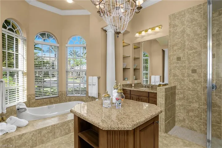 Bathroom with crown molding, vanity, a bath, a shower stall, and a chandelier