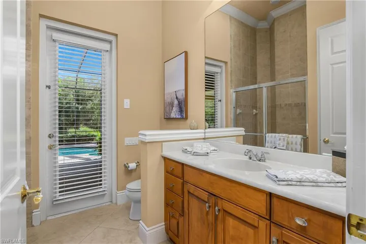 Full bathroom with a tile shower, vanity, crown molding, healthy amount of natural light, and light tile patterned floors
