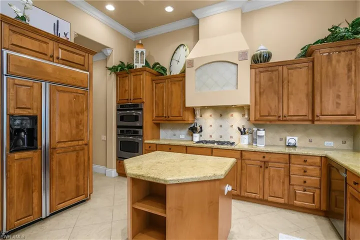 Kitchen featuring wood finish cabinets, stainless steel appliances, open shelves, light stone countertops, and crown molding