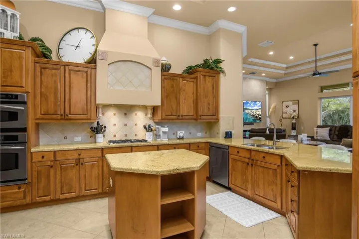 Kitchen with wood finish cabinets, ornamental molding, open shelves, a center island, and recessed lighting
