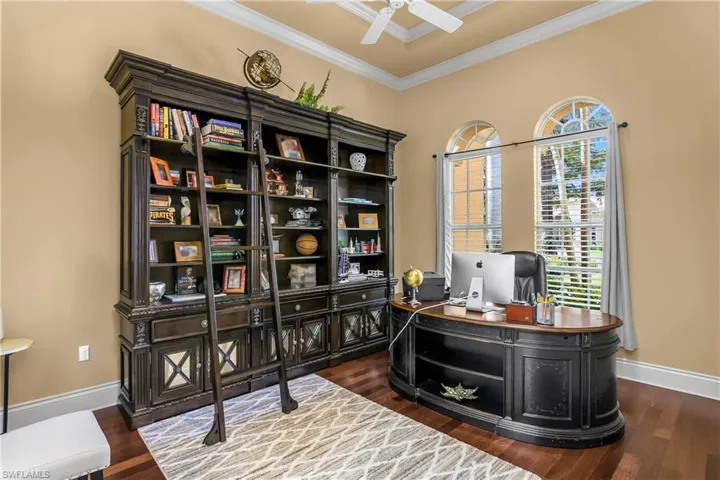 Office with crown molding, dark wood-style floors, and ceiling fan