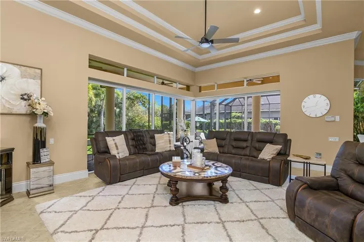 Living room featuring ceiling fan, a high ceiling, ornamental molding, and light tile patterned floors