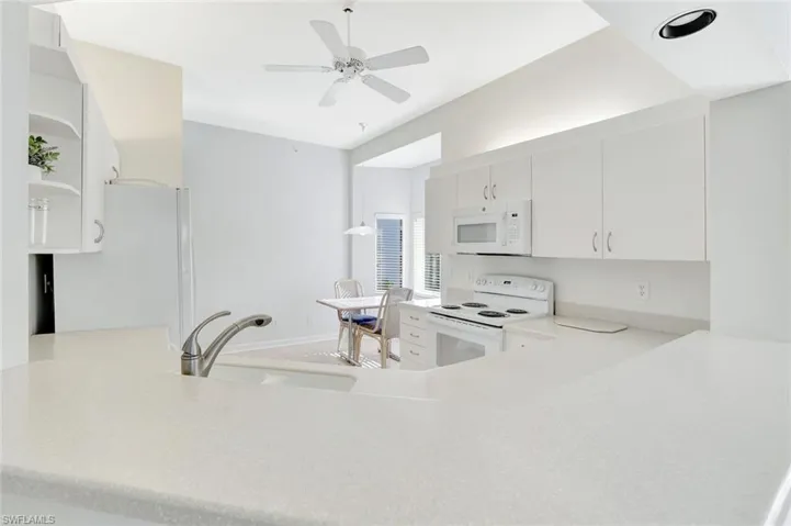 Kitchen with white appliances, white cabinets, open shelves, and a ceiling fan