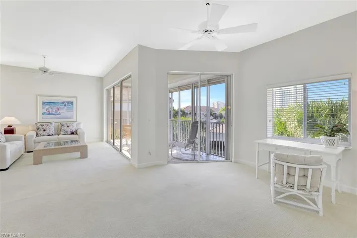 Living room with a ceiling fan, light colored carpet, and lofted ceiling