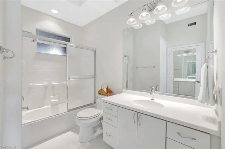 Full bathroom with vanity, bath / shower combo with glass door, and light tile patterned flooring