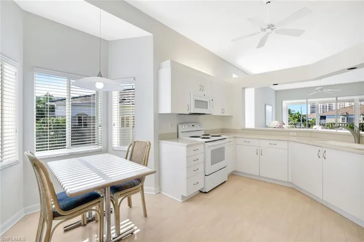 Kitchen featuring white appliances, ceiling fan, light countertops, hanging light fixtures, and white cabinets
