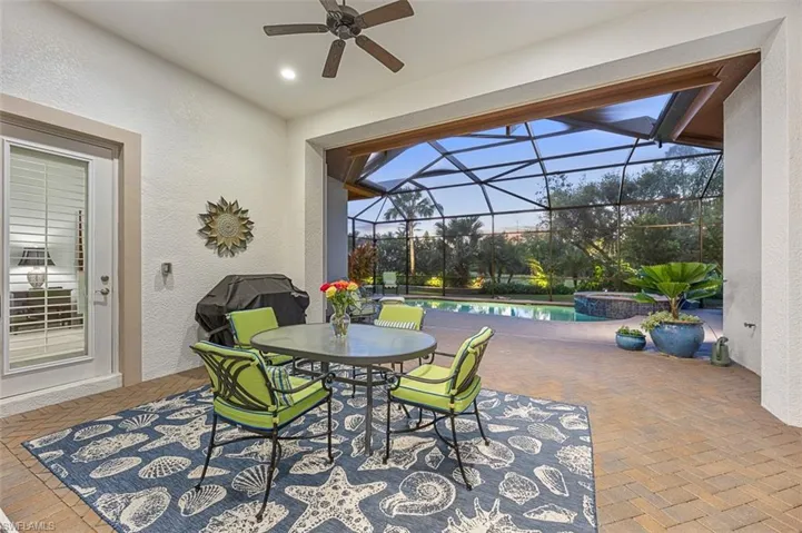 View of patio featuring glass enclosure, ceiling fan, and a swimming pool with hot tub