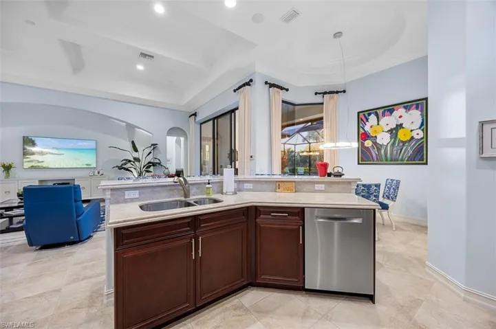 Kitchen featuring sink, stainless steel dishwasher, crown molding, dark brown cabinets, and a center island with sink
