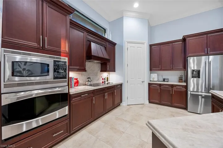 Kitchen featuring decorative backsplash, crown molding, stainless steel appliances, and custom exhaust hood