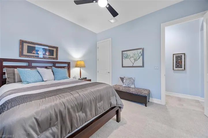 Bedroom featuring ceiling fan, light colored carpet, and lofted ceiling