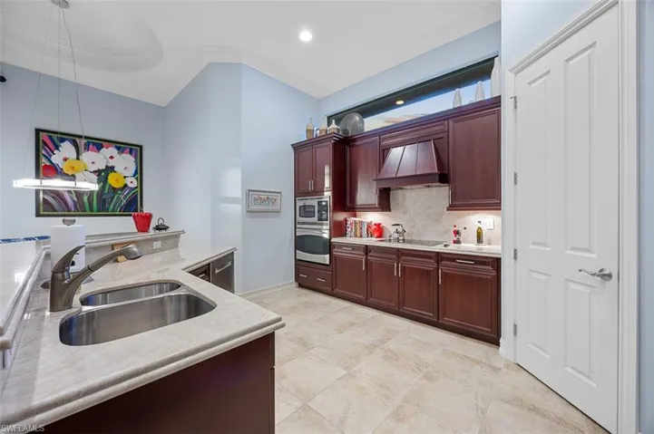 Kitchen with ornamental molding, sink, pendant lighting, backsplash, and custom exhaust hood