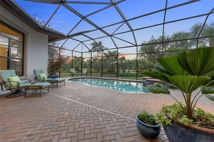 Pool at dusk with a patio and a lanai