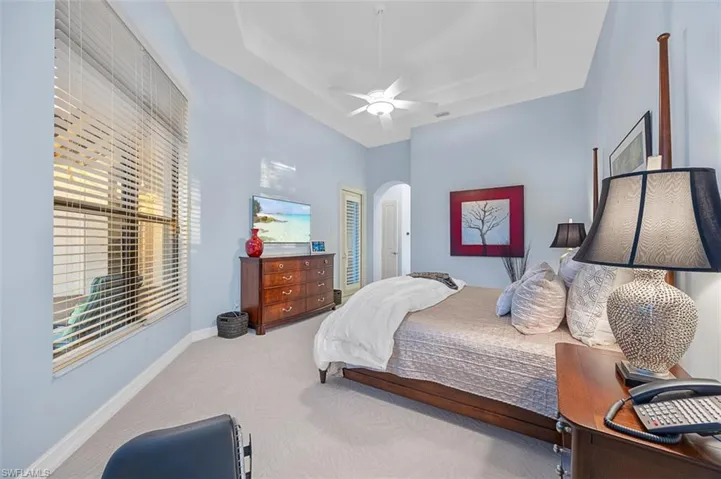 Carpeted bedroom featuring ceiling fan and a tray ceiling