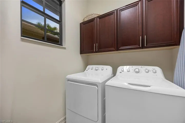 Clothes washing area featuring cabinets and washing machine and dryer
