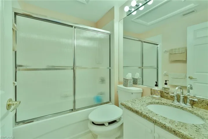 Full bath featuring combined bath / shower with glass door and vanity