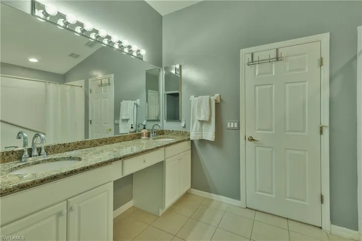Full bathroom with double vanity, light tile patterned floors, and a shower with curtain