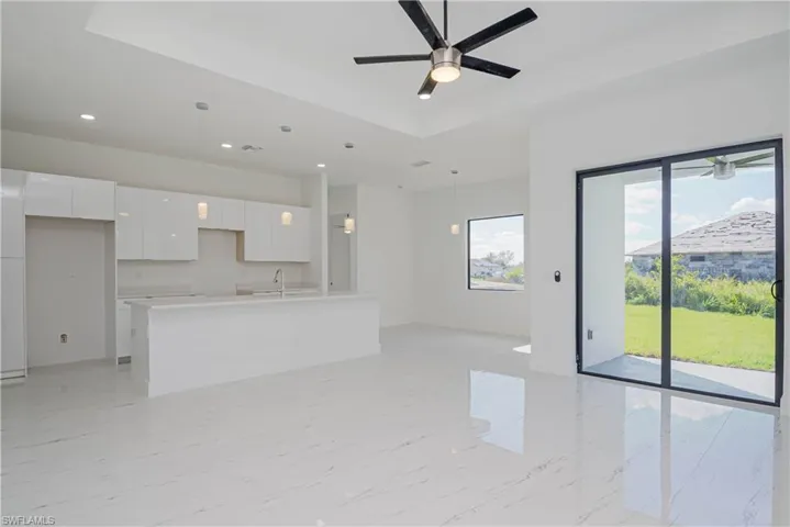 Unfurnished living room with marble finish floor, recessed lighting, a raised ceiling, a ceiling fan, and a sink