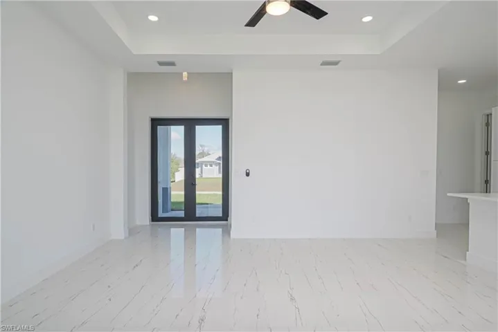 Unfurnished room featuring a raised ceiling, visible vents, baseboards, and french doors