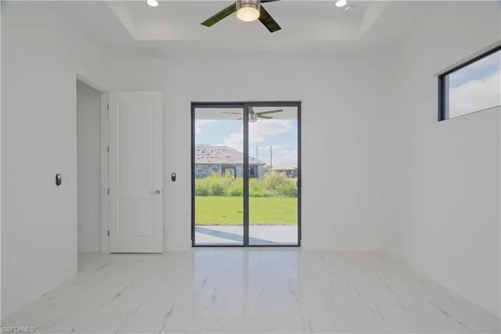 Spare room featuring marble finish floor, baseboards, and a raised ceiling