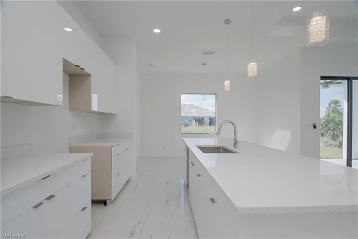 Kitchen featuring modern cabinets, marble finish floor, a large island with sink, a sink, and recessed lighting