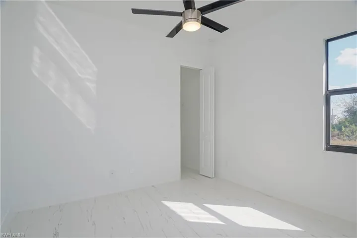 Spare room featuring marble finish floor, a ceiling fan, and baseboards