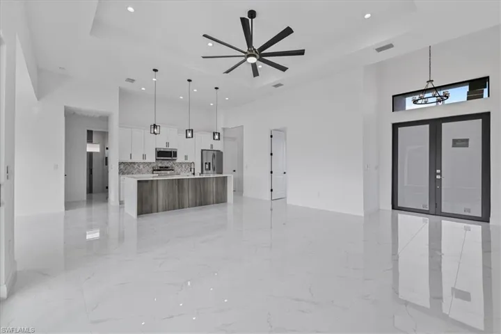Unfurnished living room featuring a high ceiling, french doors, recessed lighting, a tray ceiling, and light marble finish flooring