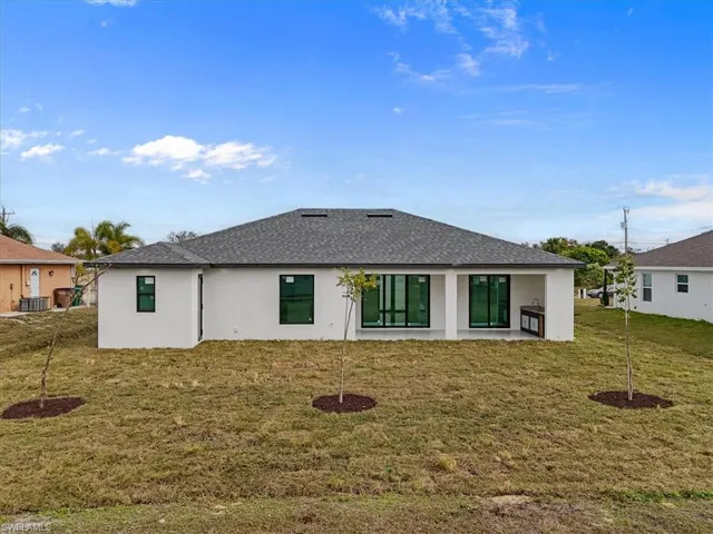 Rear view of house with stucco siding, a patio area, and a yard