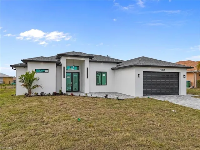 Prairie-style house with a front yard, french doors, stucco siding, and decorative driveway