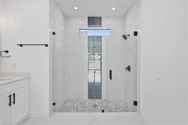Bathroom featuring a marble finish shower and vanity
