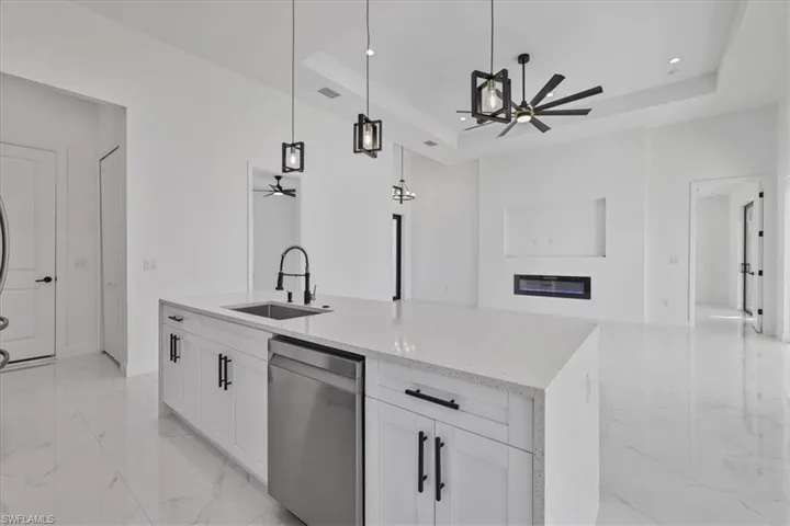 Kitchen featuring a ceiling fan, decorative light fixtures, light stone counters, white cabinets, and recessed lighting