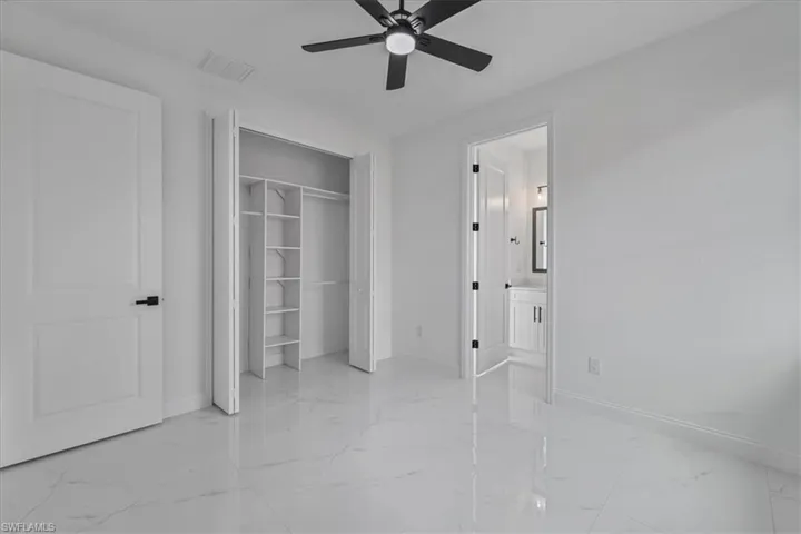 Unfurnished bedroom featuring a ceiling fan, a closet, and ensuite bathroom