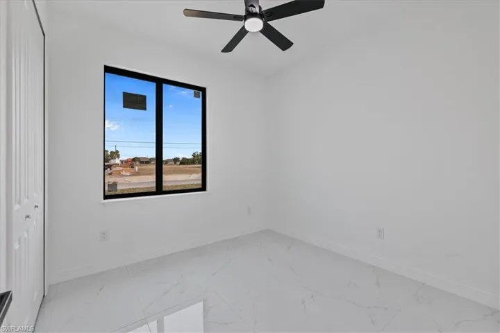 Spare room with light marble finish floors and a ceiling fan