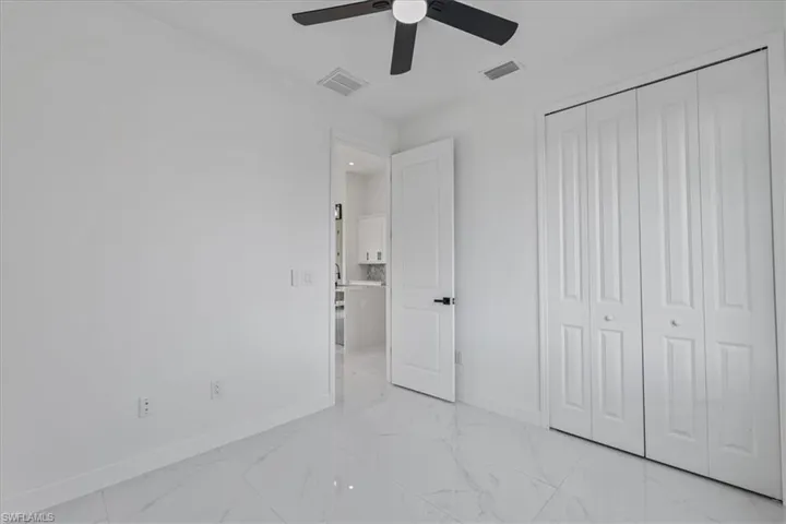 Unfurnished bedroom featuring a ceiling fan, a closet, and light marble finish floors
