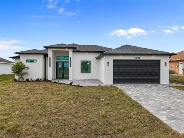 Prairie-style home featuring a front yard, stucco siding, decorative driveway, and french doors